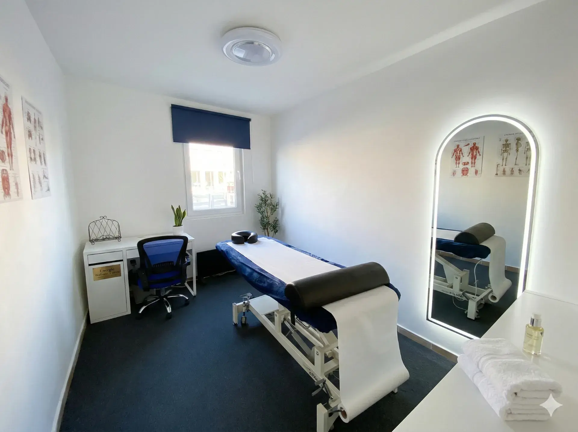 Therapy room at Archway Wellness Centre with treatment bed, arch mirror, and anatomy charts