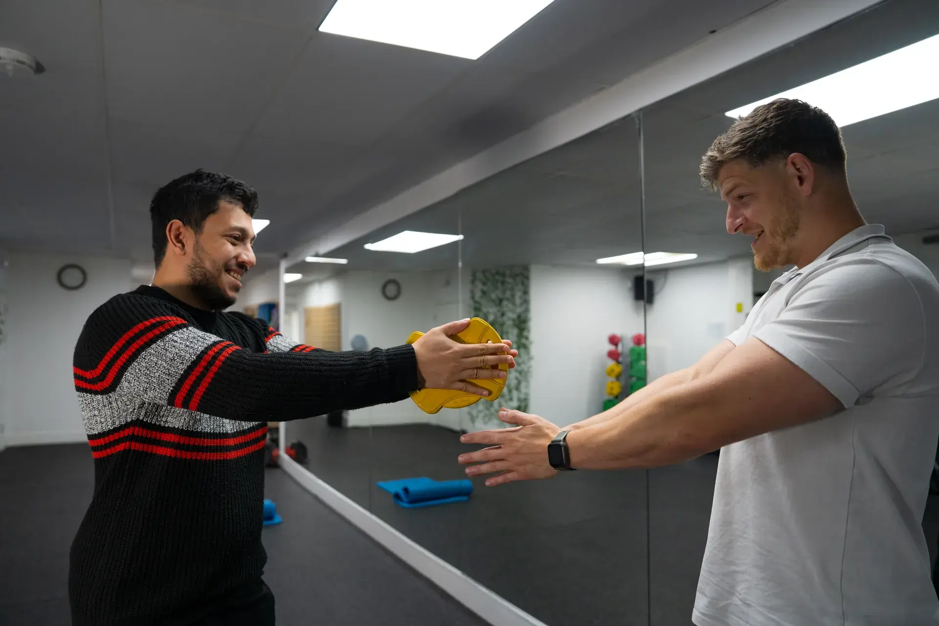 Physiotherapist guiding patient through functional movement exercise with weight plate