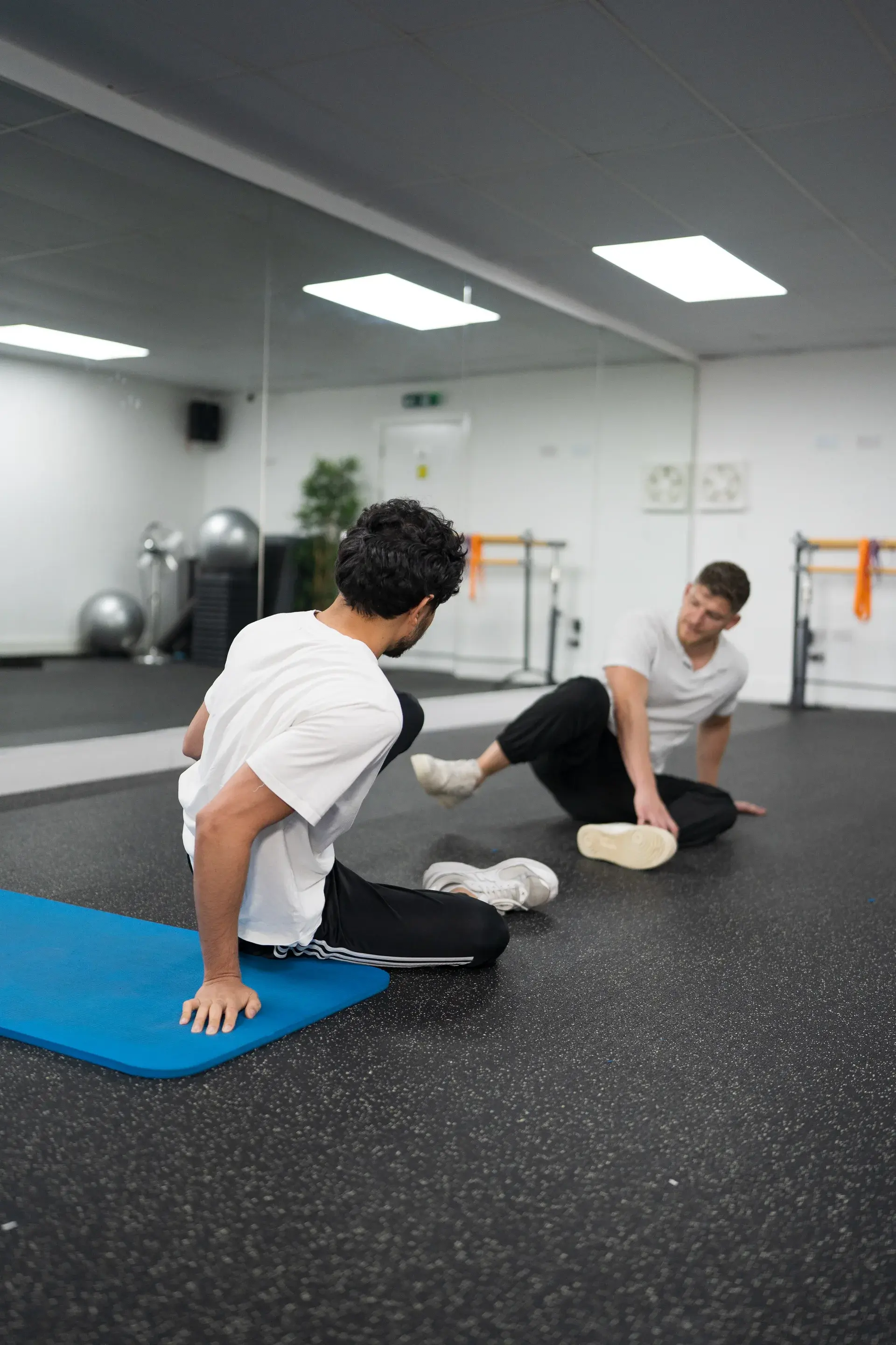 Physiotherapist and patient doing floor-based mobility exercises in the gym