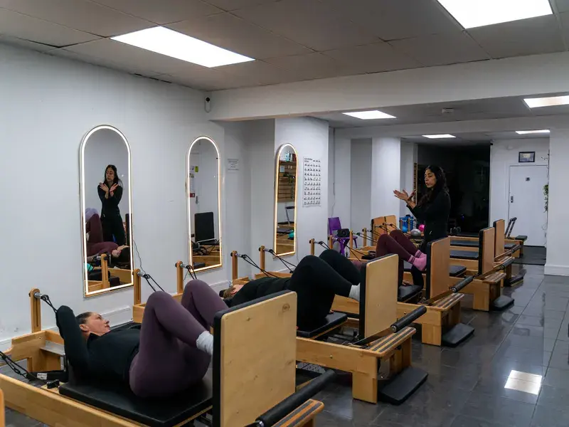 Reformer Pilates class in the studio with arched mirrors