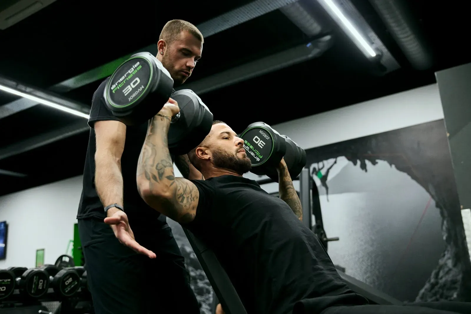 Personal trainer spotting client during dumbbell shoulder press at Archway Wellness Centre