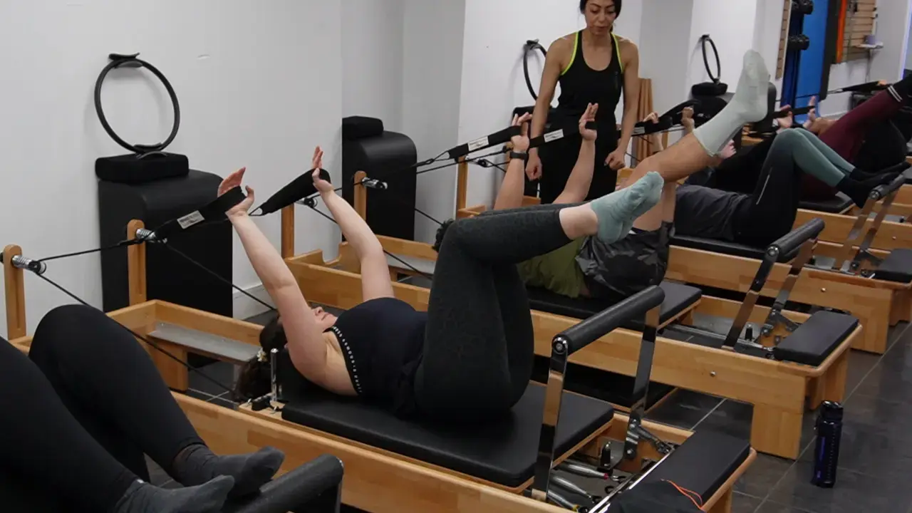 Instructor guiding a client through a reformer Pilates class at Archway Wellness Centre
